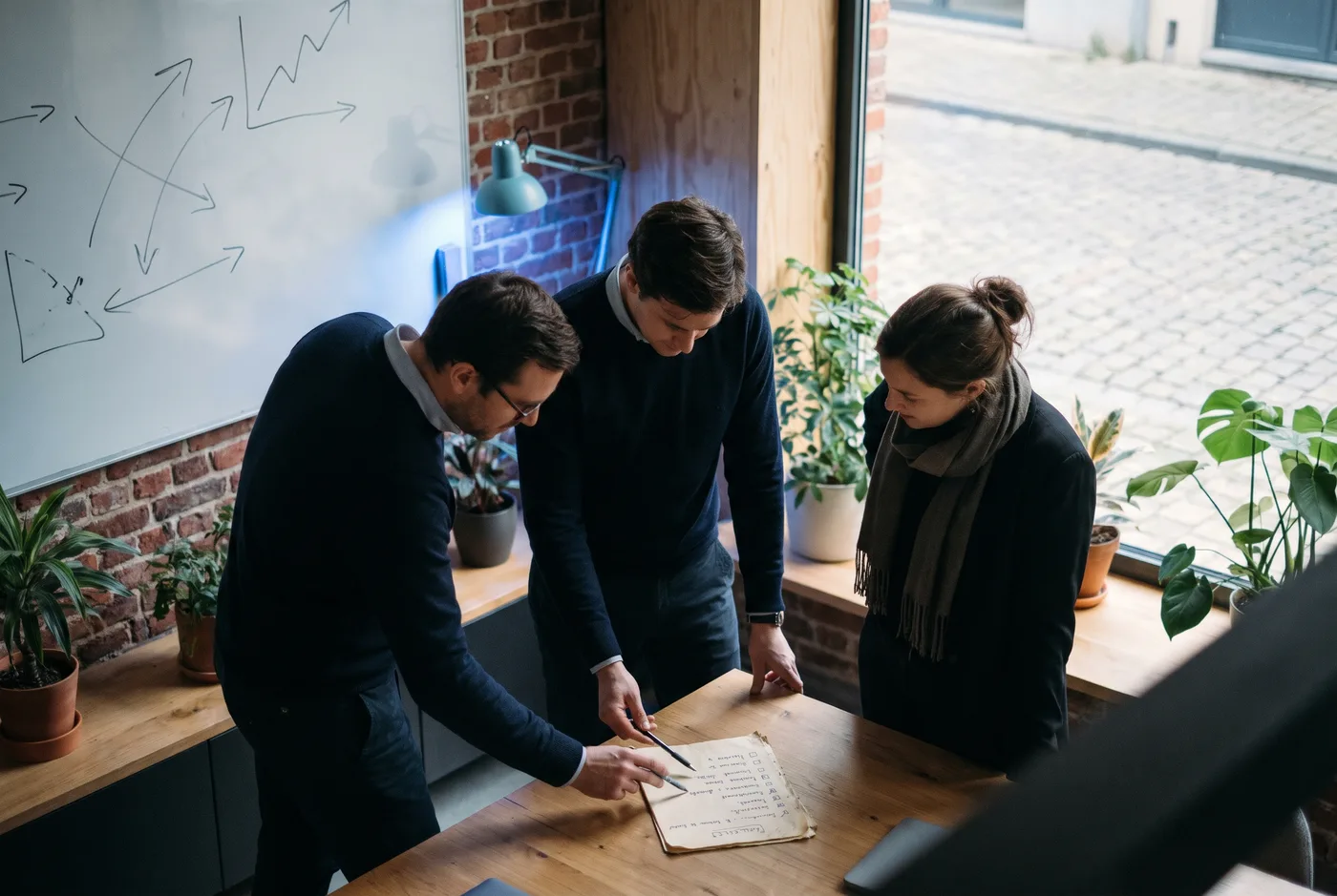 Klein team bespreekt een checklist op papier rond een tafel in een Vlaams kantoor