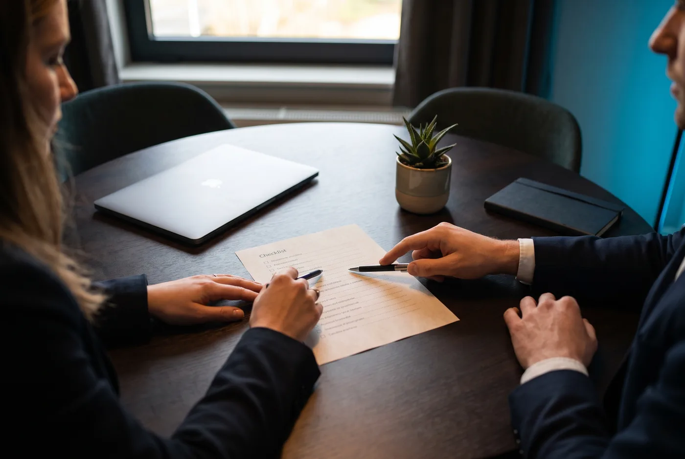 Twee ondernemers overlopen samen een checklist aan een vergadertafel