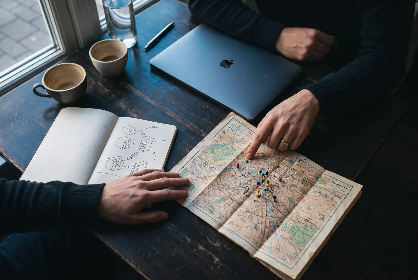 Twee mensen bespreken een lokaal SEO-plan aan een bureau met notitieboek en kaart